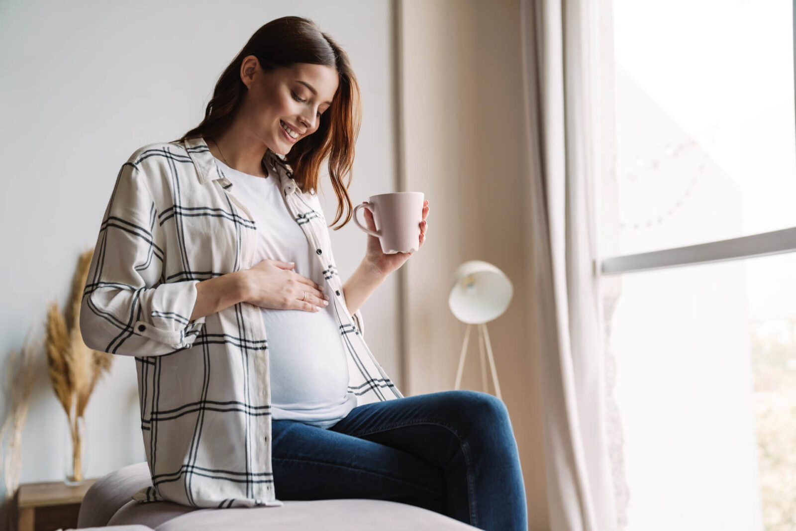 Beautiful happy pregnant woman smiling and drinking coffee