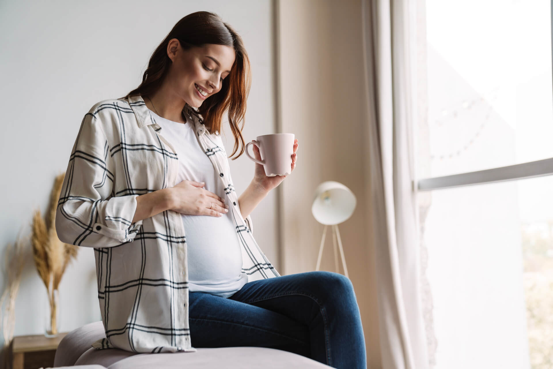 Beautiful happy pregnant woman smiling and drinking coffee