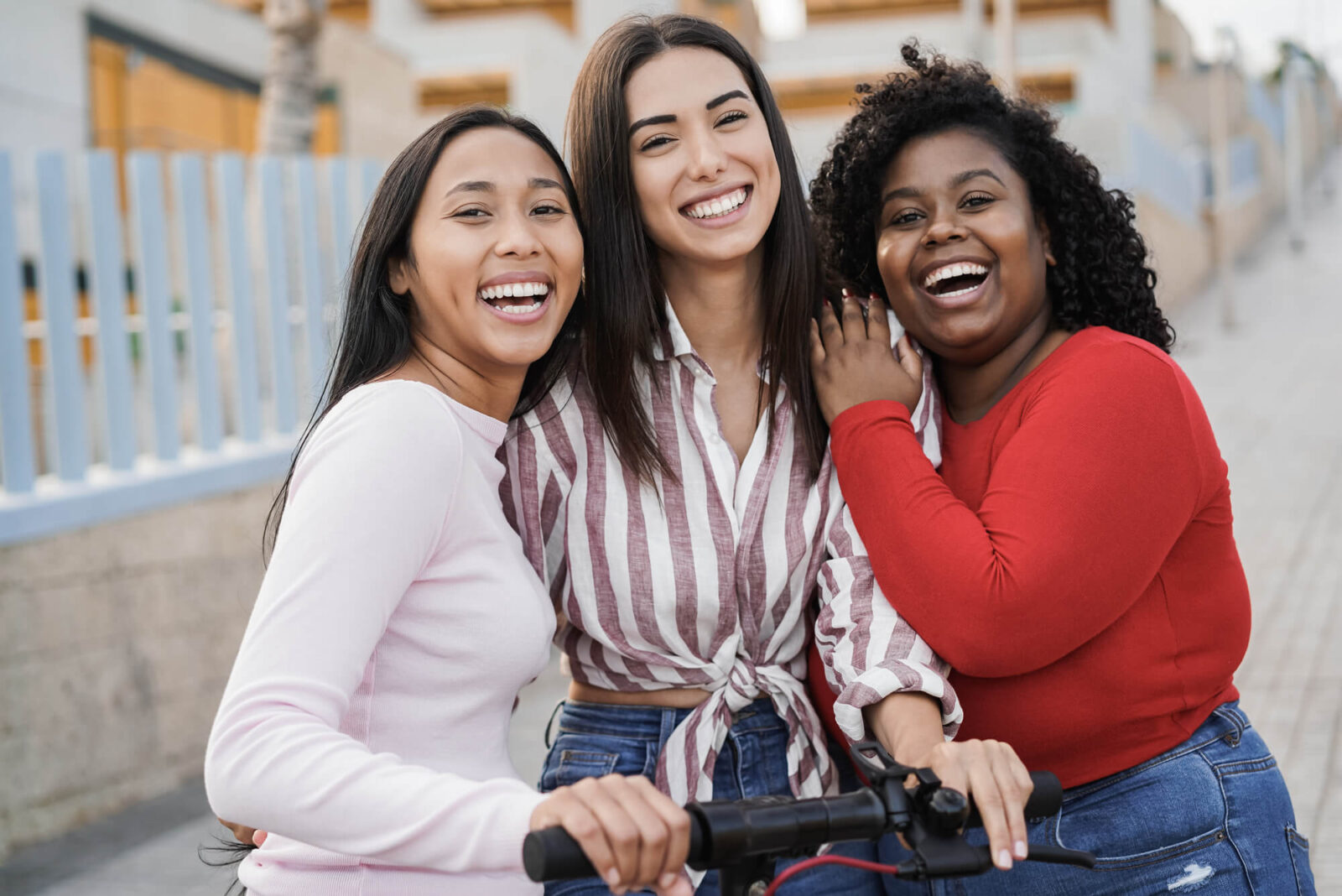 Happy latin girls having fun with electric scooter