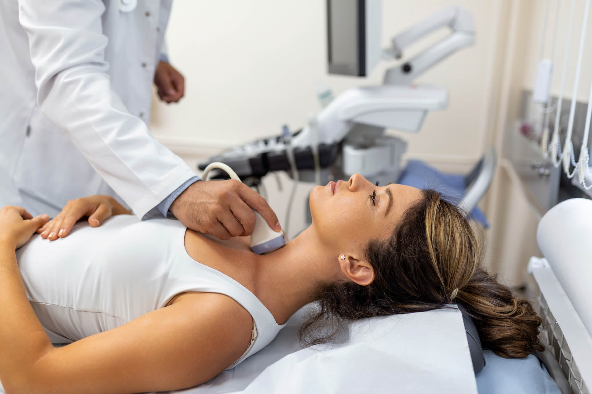 Doctor making ultrasound of thyroid gland to woman